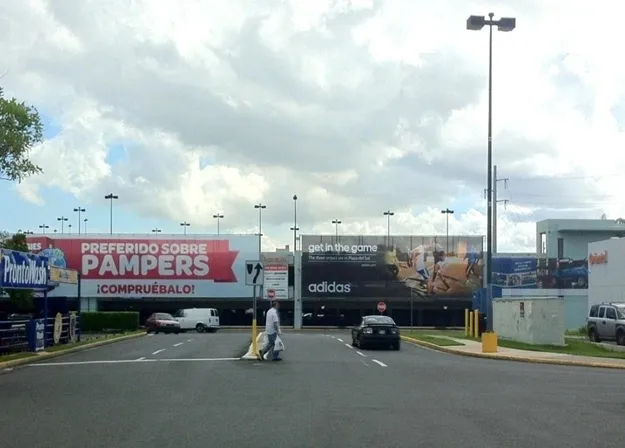 A street in front of a shopping center with a lot of cars.