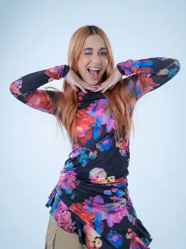 A woman in a floral dress is posing for the camera.