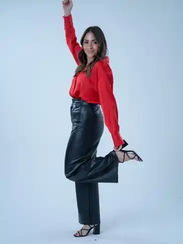 A woman in a red top posing on a white background.