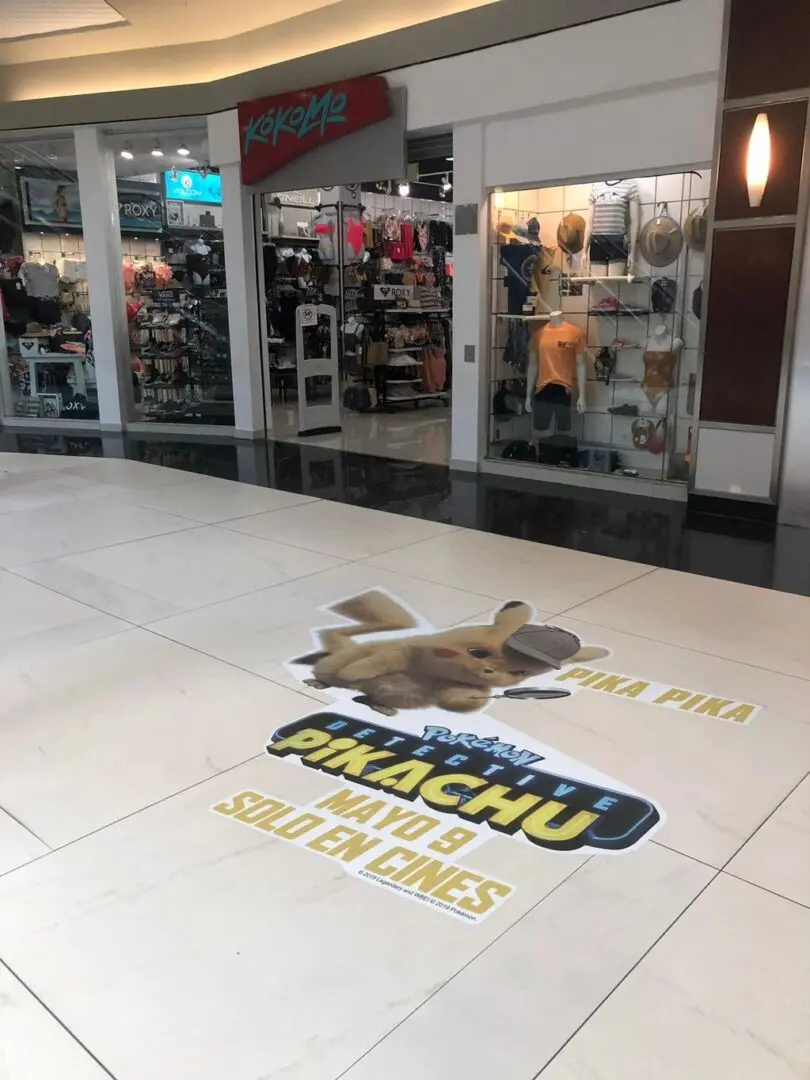 The floor of a shopping mall has a picture of a pokemon.