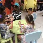 A group of children sitting at a table in a store.